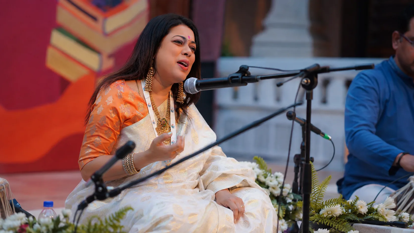 Barnali Chattopadhyay performing on a festival stage before carved stone pillars