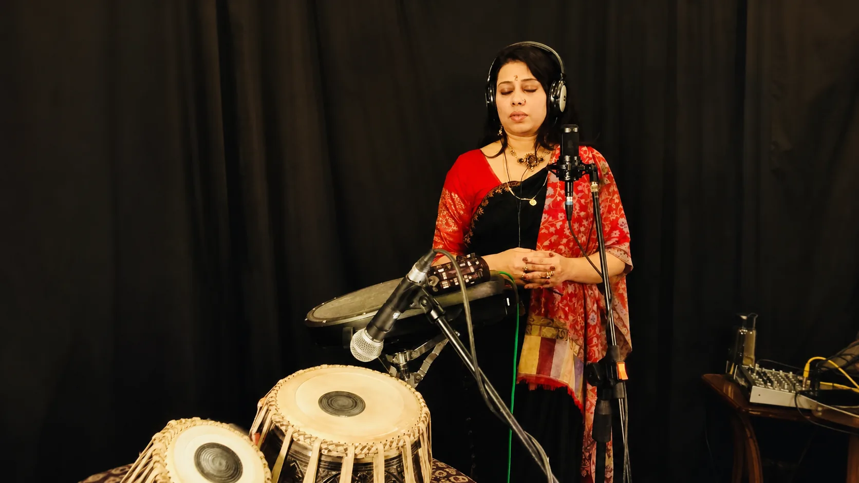Barnali Chattopadhyay recording in a studio, wearing headphones at a condenser microphone